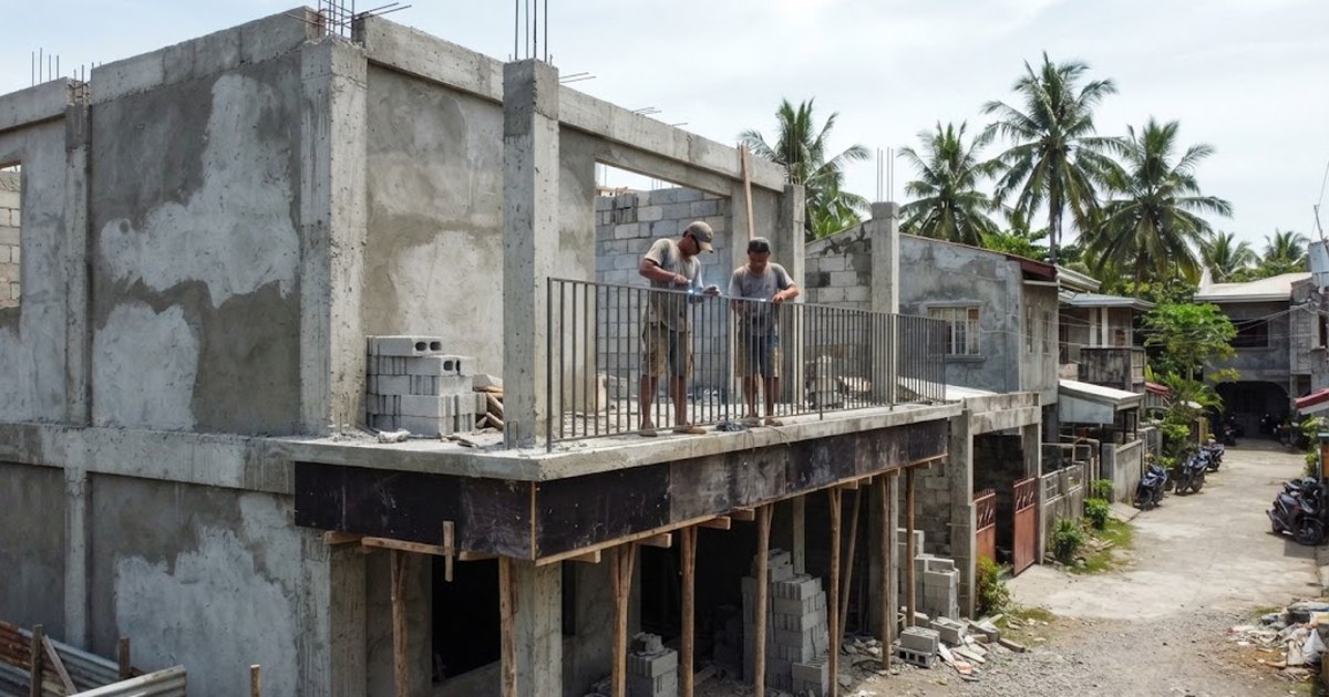 Workers on a newly cast concrete balcony with formwork props still underneath