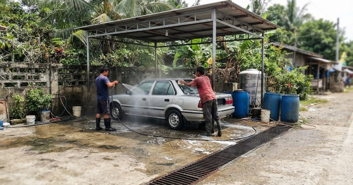 A car being hand-washed in a small covered car wash bay