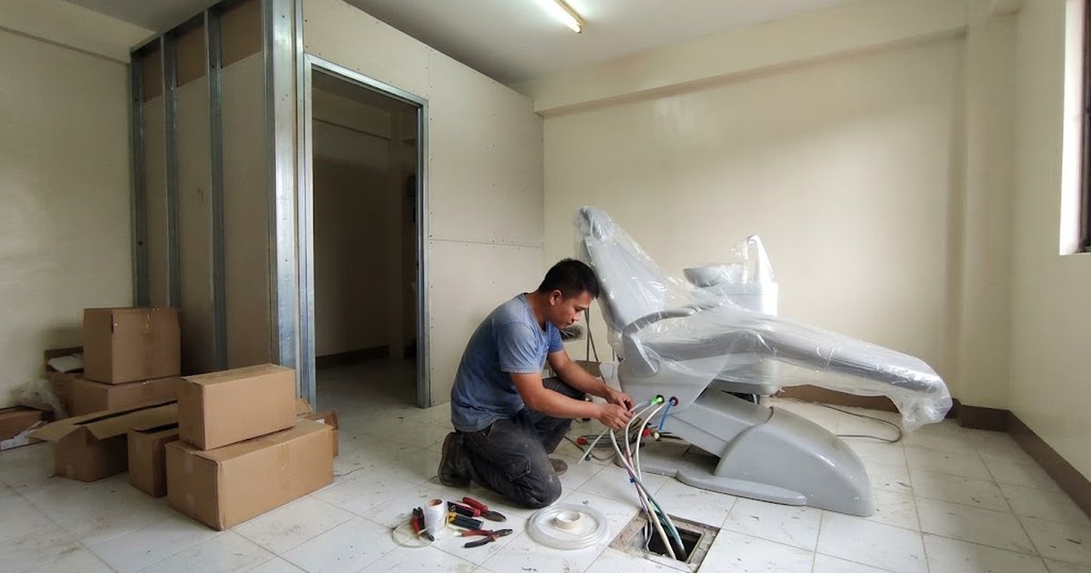 Technician connecting the water and suction lines under a new dental chair