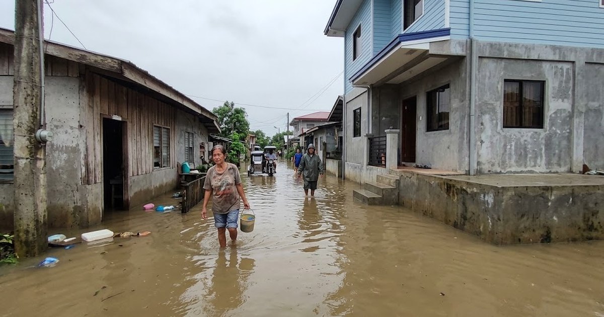Flooded street beside houses with raised floor levels in a Philippine neighbourhood