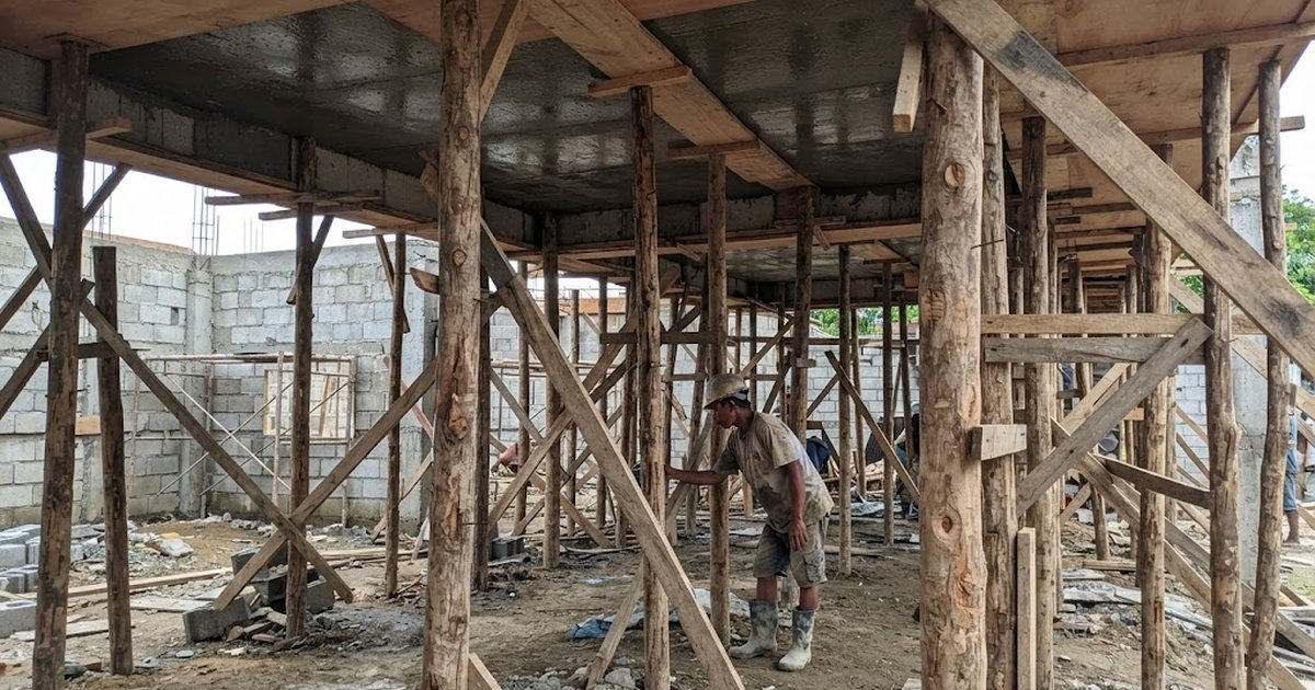 Plywood formwork and coco lumber props supporting a freshly poured second-floor concrete slab at a house construction site in the Philippines