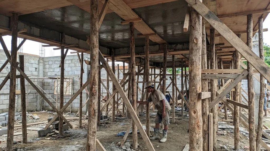 Plywood formwork and coco lumber props supporting a freshly poured second-floor concrete slab at a house construction site in the Philippines
