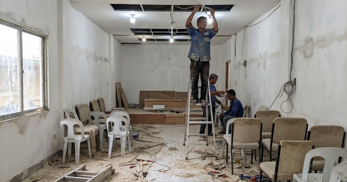 Electrician installing ceiling lights in a funeral chapel under renovation