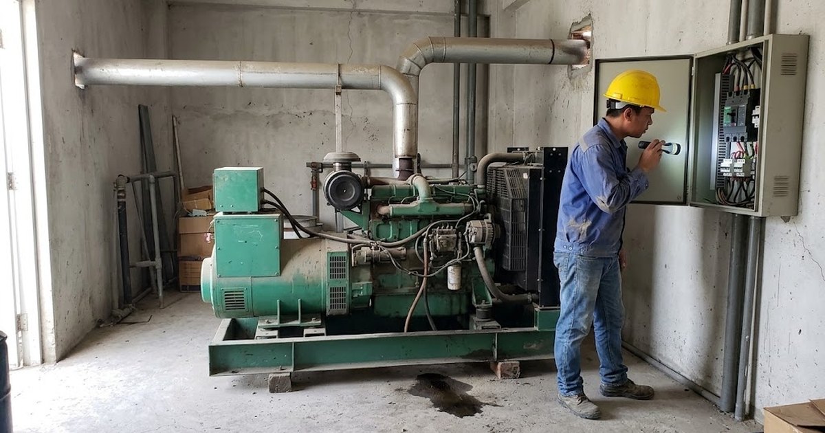Electrician checking the control panel of a diesel standby generator in a generator room