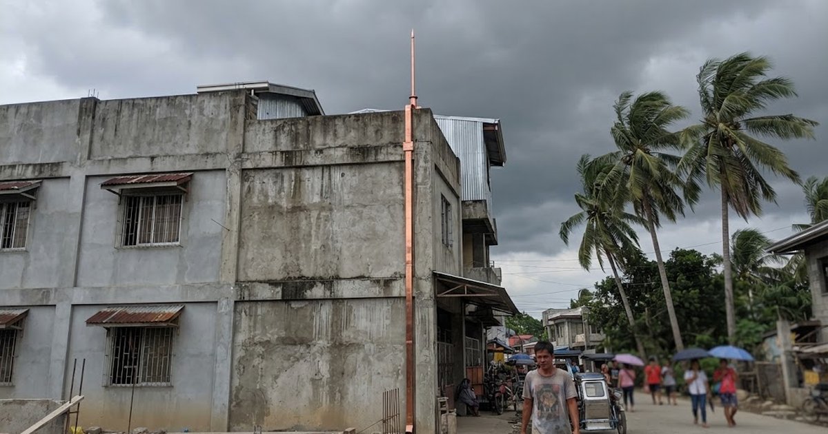 Lightning rod and copper down conductor on the roof edge of a concrete building in the Philippines under a stormy sky
