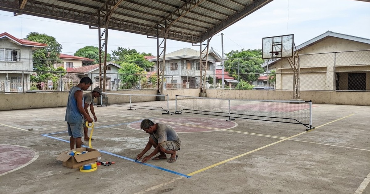 Basketball court being converted with new pickleball lines and portable nets on a Philippine barangay covered court