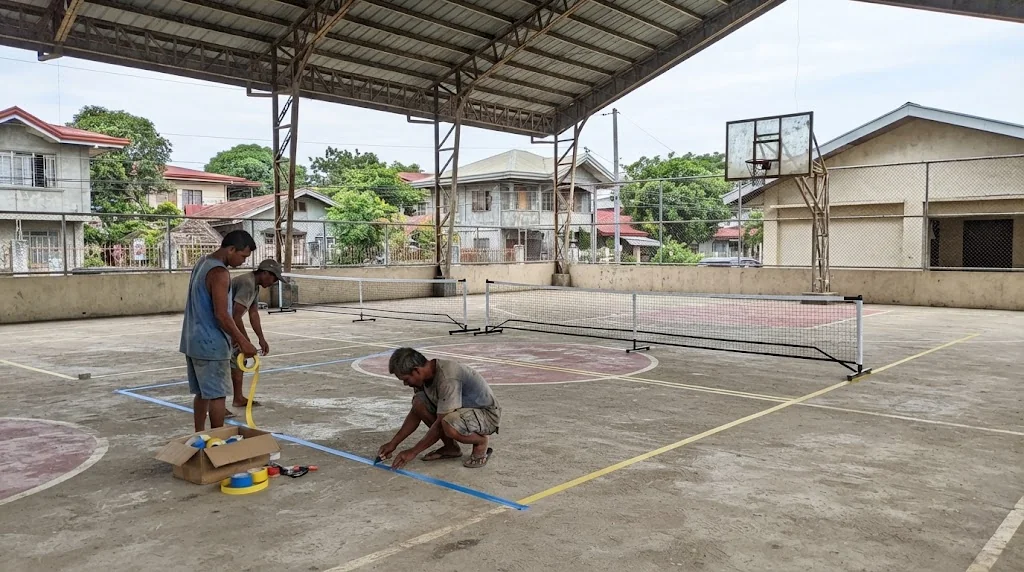 Basketball court being converted with new pickleball lines and portable nets on a Philippine barangay covered court