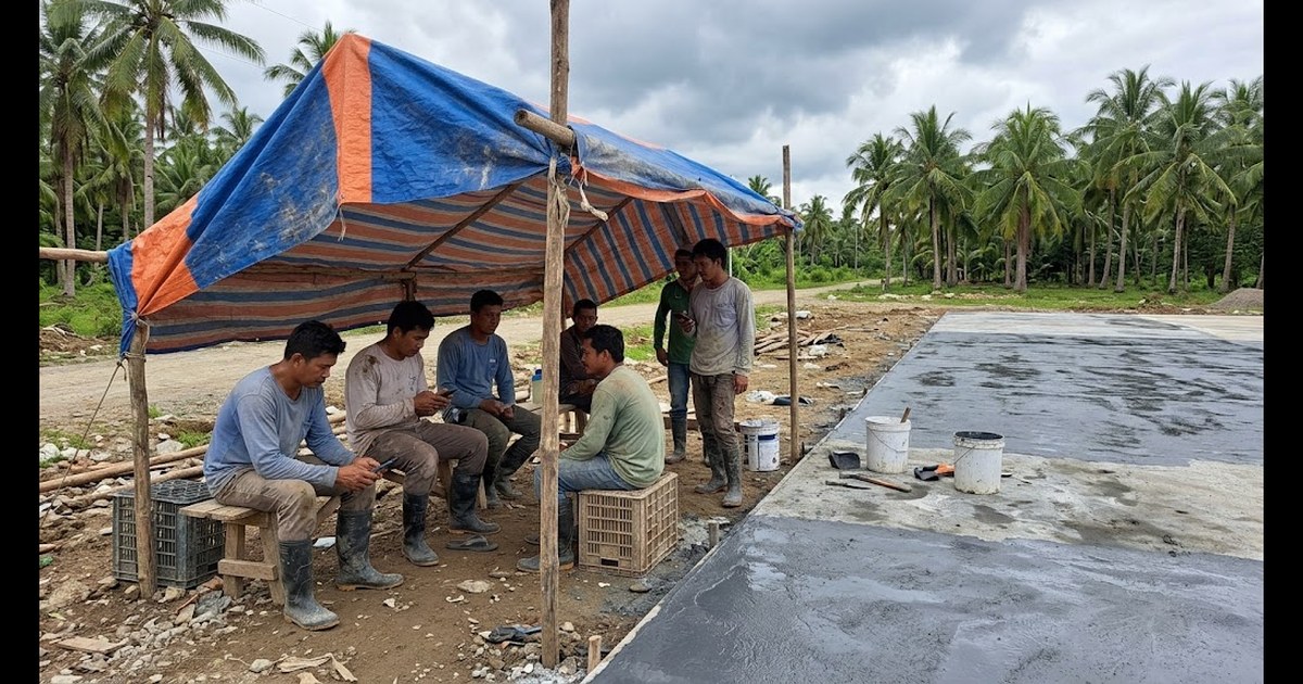 Filipino crew waiting under a tarp as rain clouds gather over a freshly primed concrete court slab beside coconut trees in Negros Oriental
