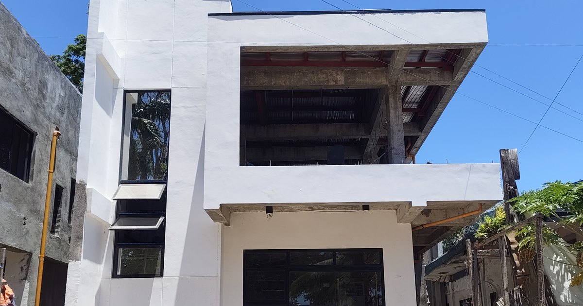 A Philippine house part-finished, painted facade with an unfinished upper floor