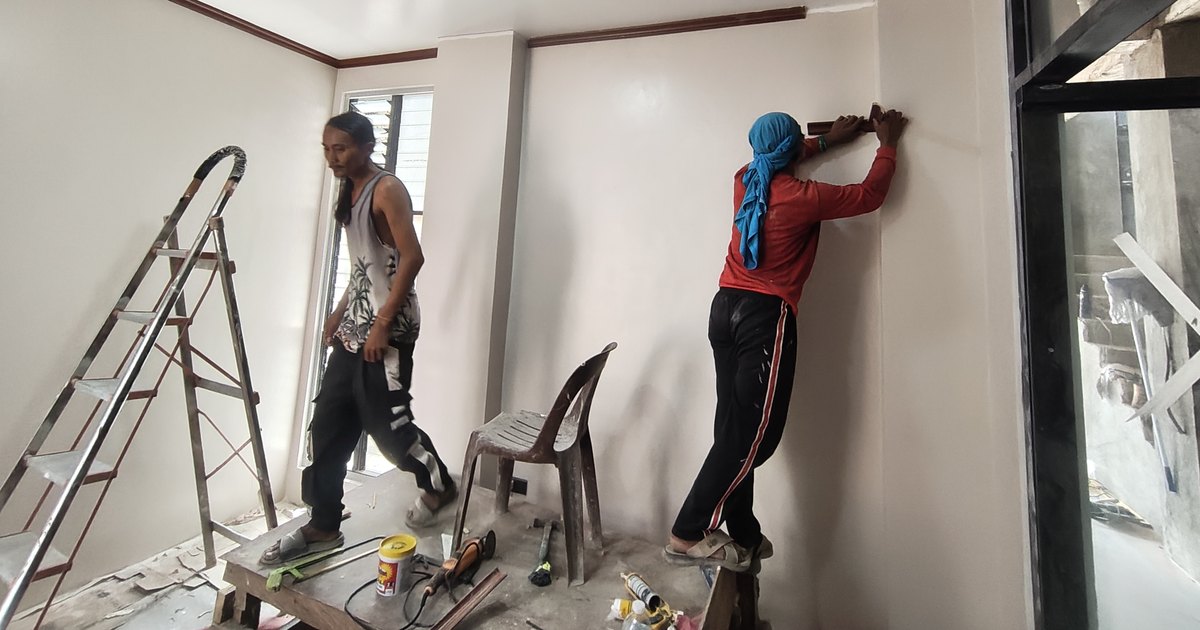 Workers applying skim coat and finishing an interior wall on a Philippine house
