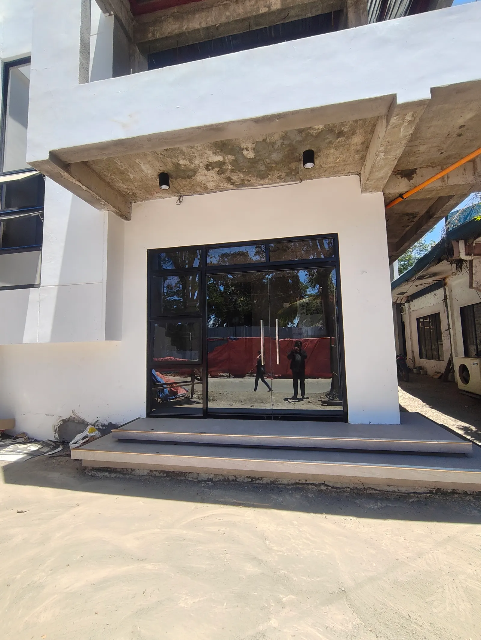 Glass entrance doors under a concrete overhang at the GAD Building — Manjuyod