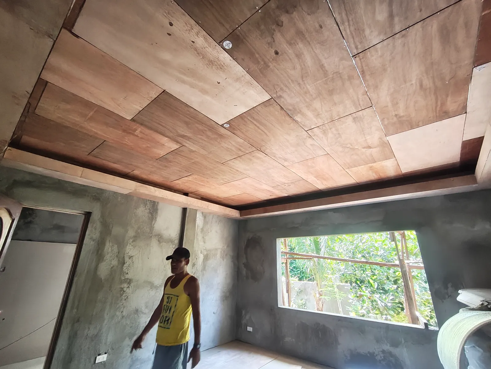 Worker installing a wood ceiling panel inside a room under construction — ongoing project, Repollo Residence, Tanjay City
