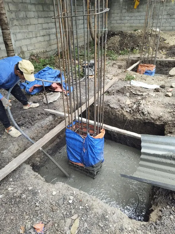 Concrete being poured around a column rebar cage in a footing excavation — pickleball court facility, Manjuyod