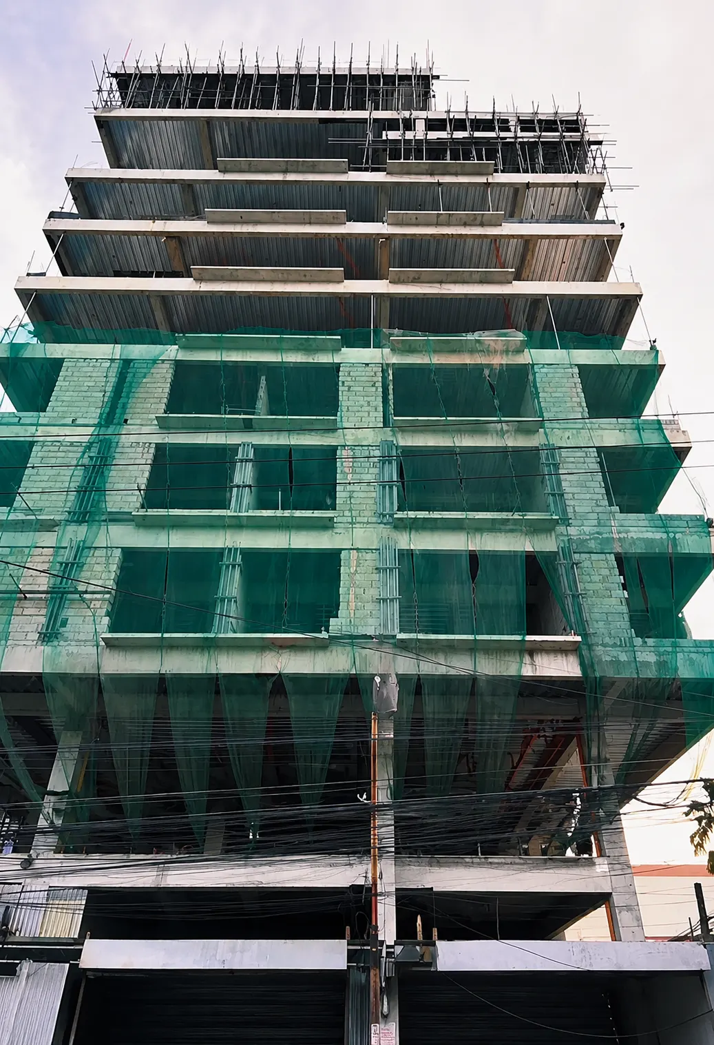Close-up of the Angeles City building facade before collapse showing scaffolding and open slab edges