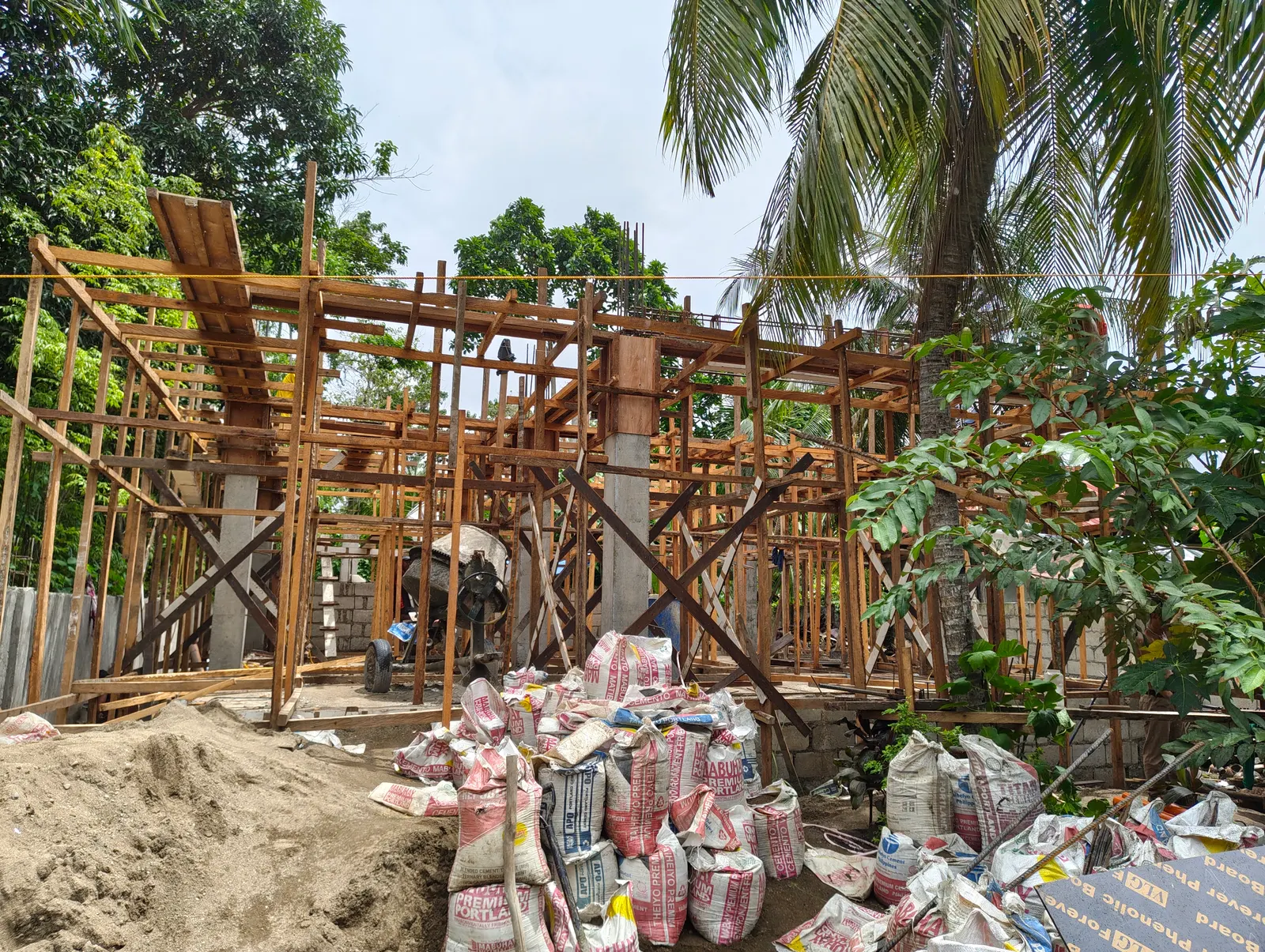 Workers laying CHB walls with a cement mixer operating on site — AEDO Construction Philippines