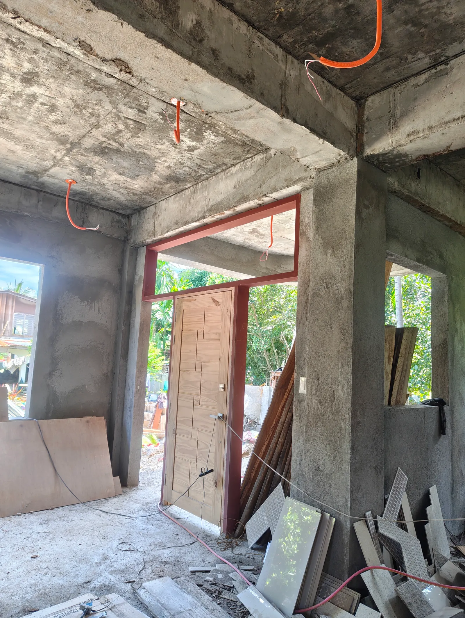 Interior of a concrete house showing orange electrical conduits embedded in walls and concrete ceiling — rough-in MEP stage Philippines